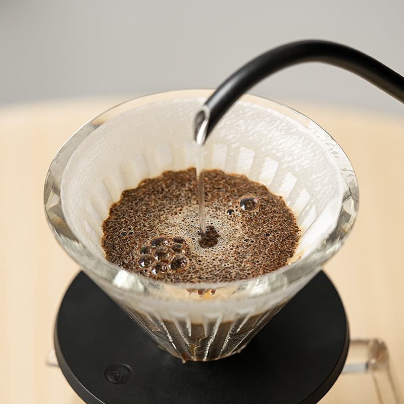 Vertido de agua sobre café en un dripper Crystal Eye de base negra