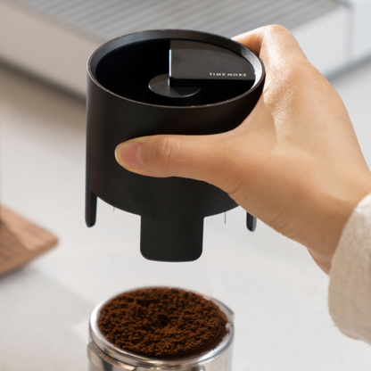 Mano apoyando el Timemore Autospin sobre la canastilla con café molido