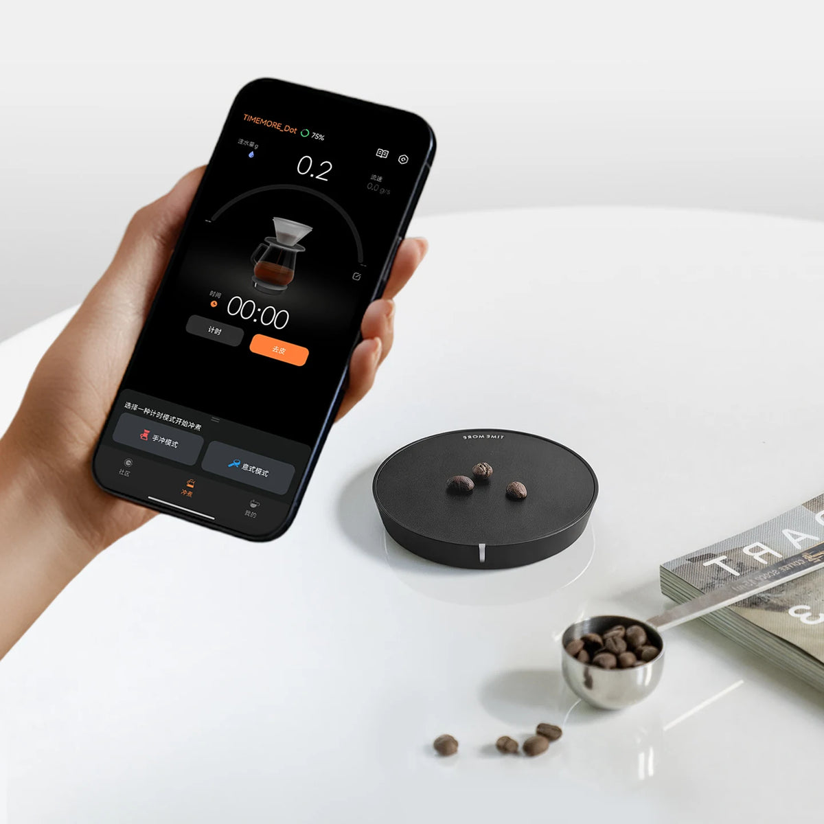 Teléfono mostrando la app de café junto a una Timemore Dot negra