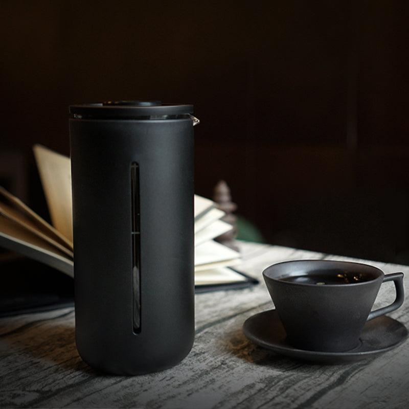 U French Press sobre una mesa con café y un libro